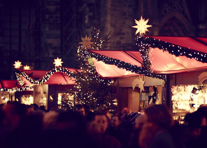 Das Bild zeigt beleuchtete Buden auf einem Weihnachtsmarkt
