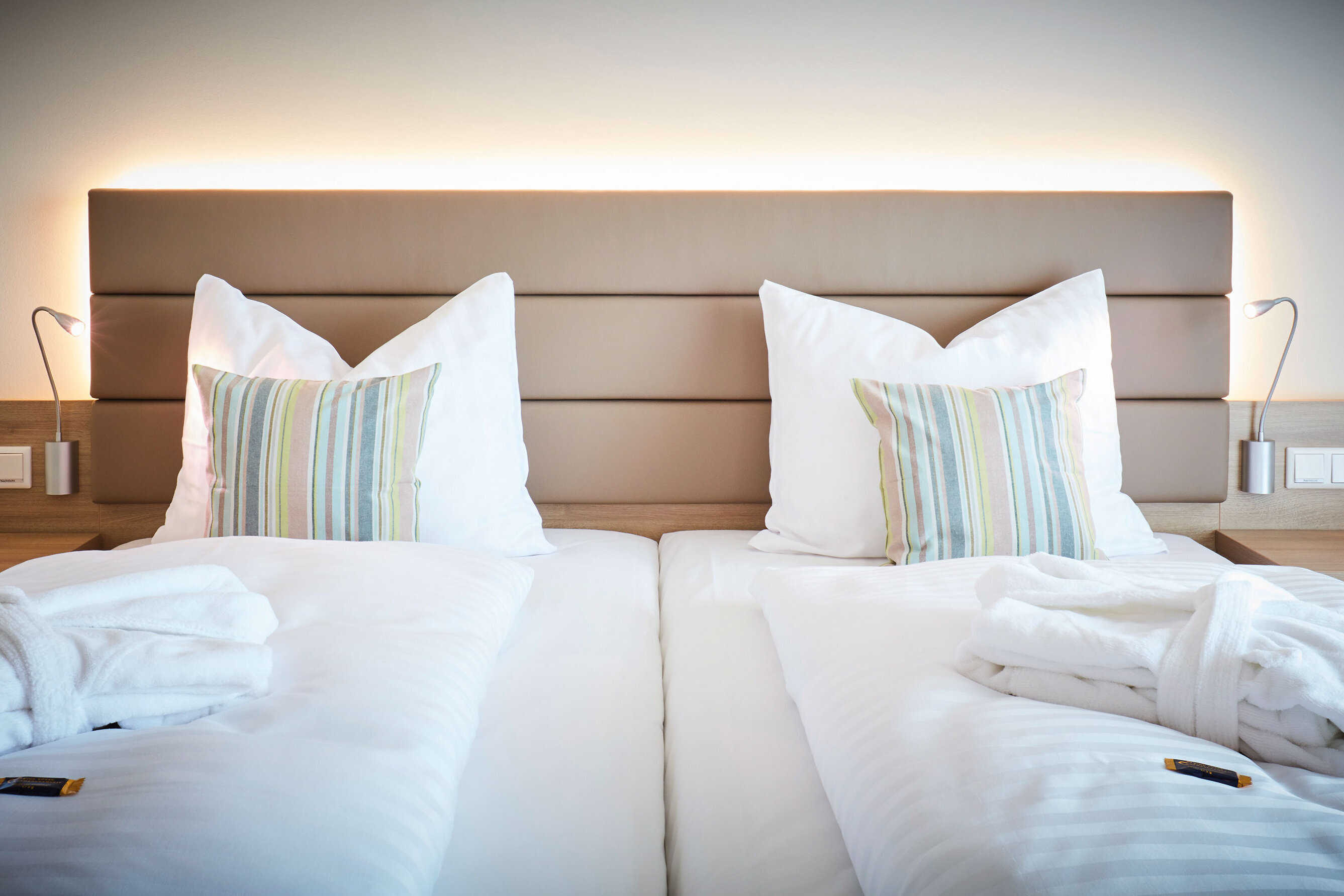 Das Bild zeigt das Bett im Doppelzimmer Komfort, auf dem auf jeder Seite ein Bademantel liegt 